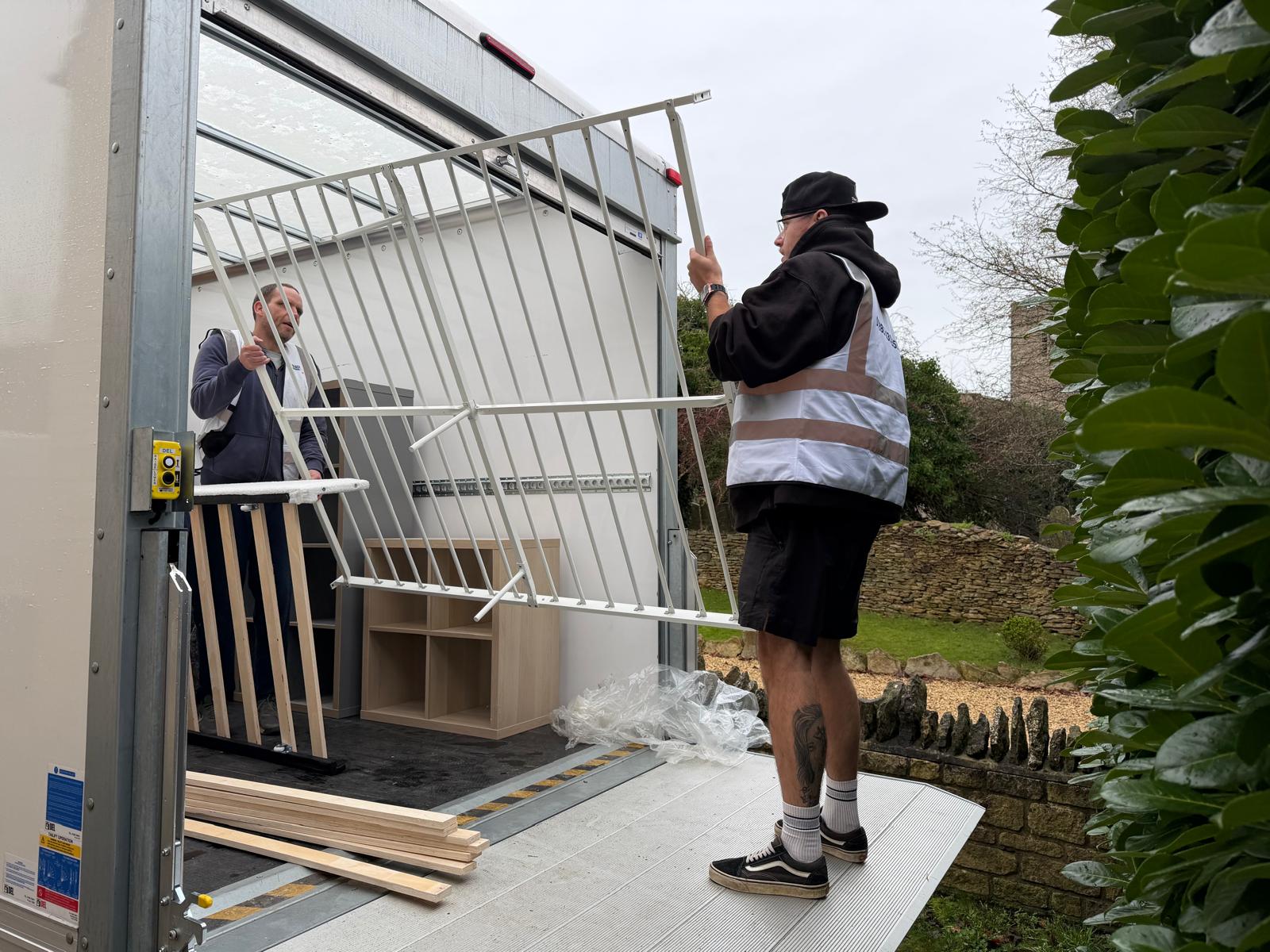 Removals team loading furniture onto a van tail lift