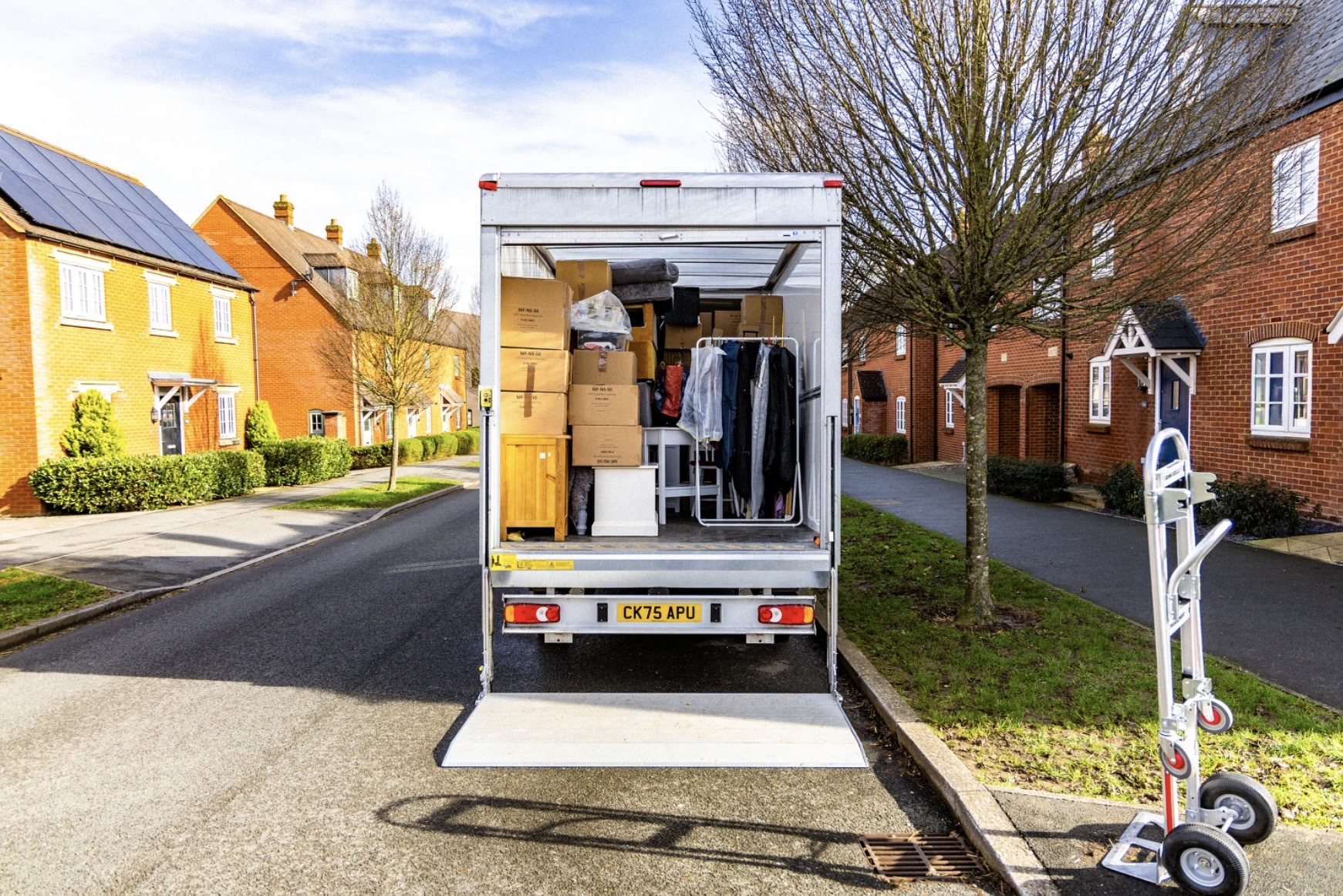 Delivery van parked on a residential street with its tail lift down